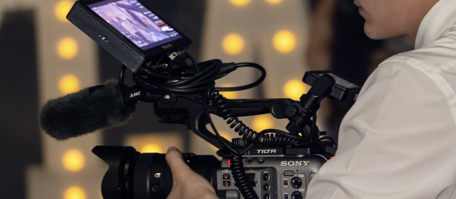 An AL Media Group videographer operating a cinema camera at an event
